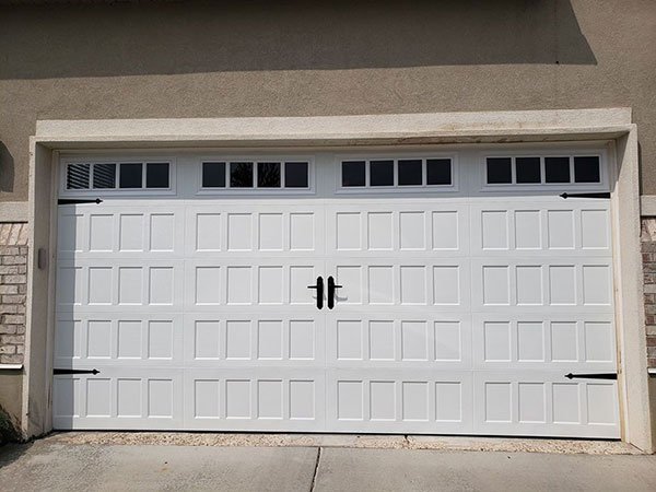 A white, faux wood residential garage door with glass panels at the top