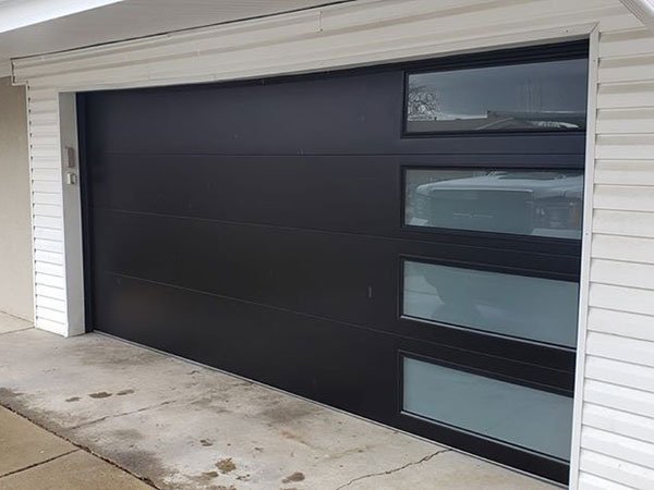 Outside view of a matte black garage door with glass panels on its right side