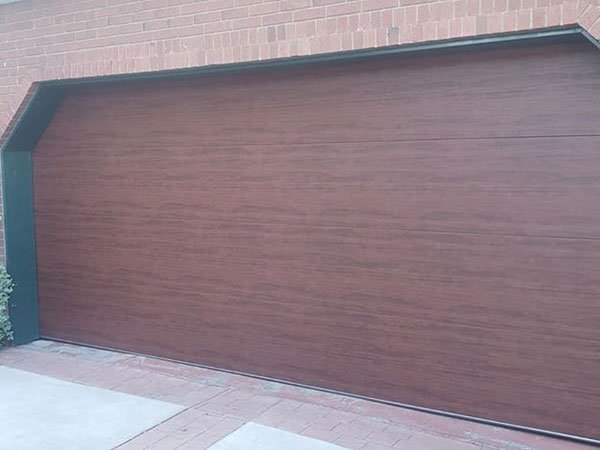 Exterior view of a residential 16 ft. x 17 ft. garage door with faux wood panels