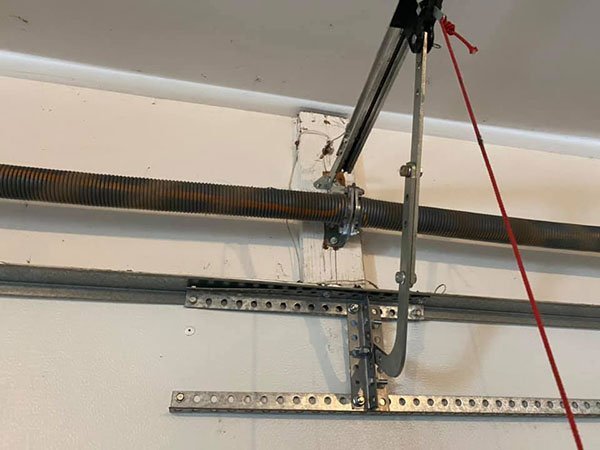 A garage door mechanism right above the entrance, showing the curved door arm, pulley, and torsion spring