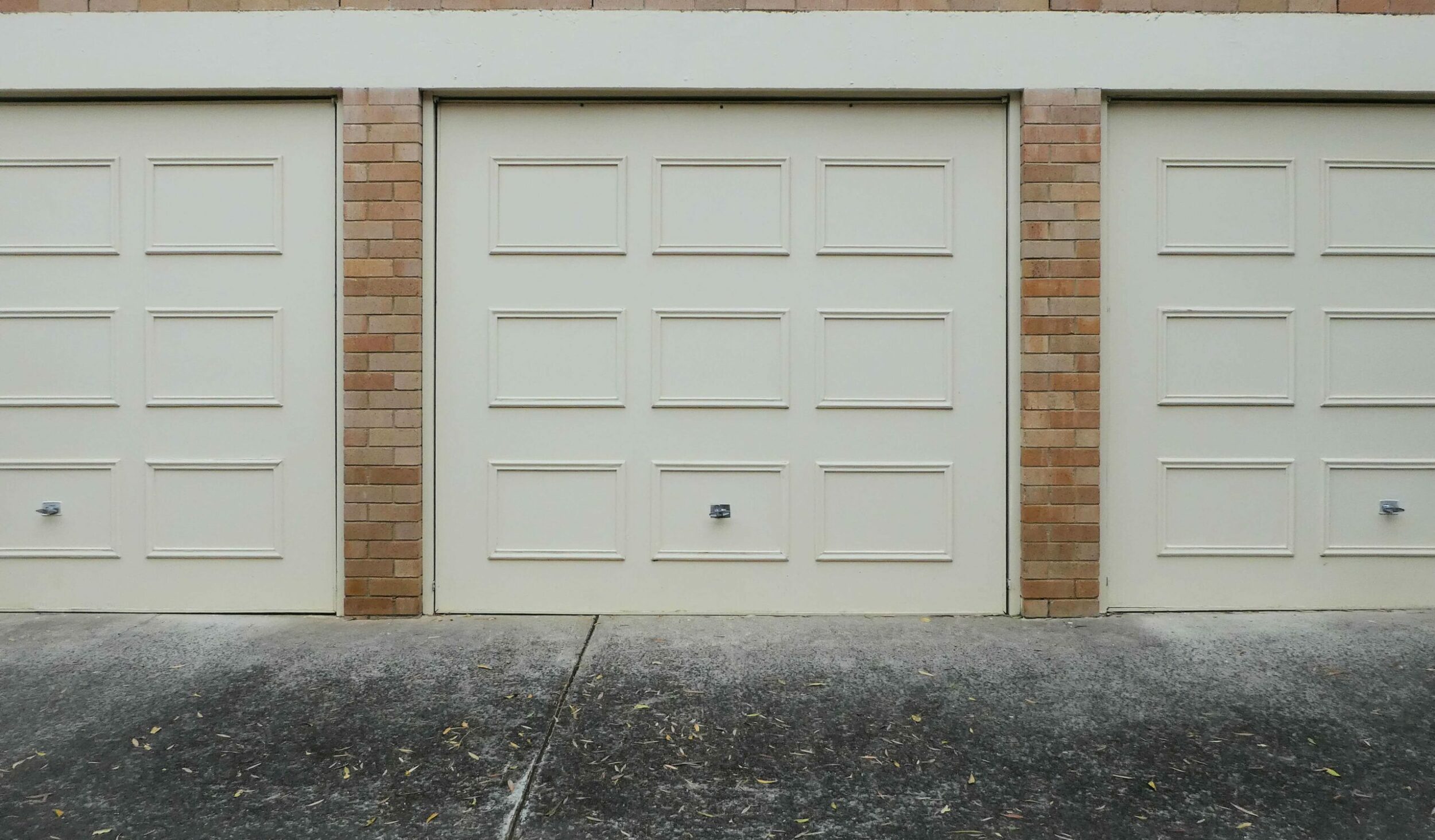 Cream Garage Doors with Wood panels on blonde brick