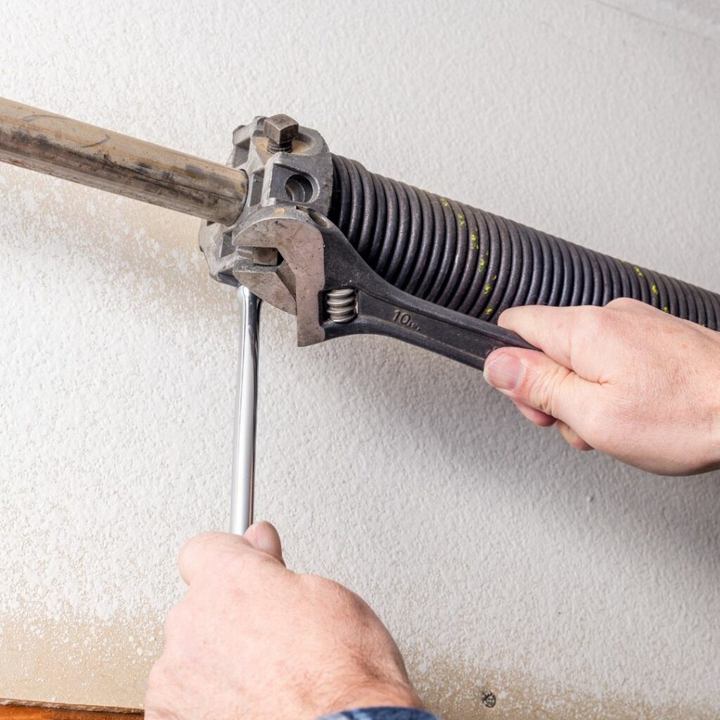 an image showing a repairman fixing a broken garage door spring
