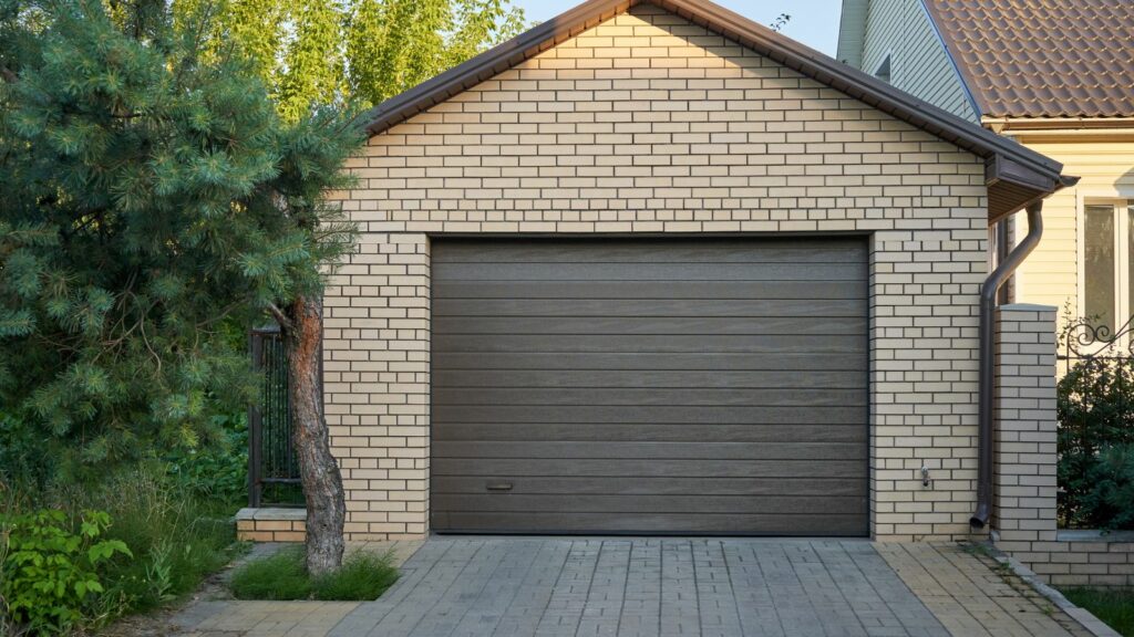 Well designed garage made of bricks and the garage door painted with brown