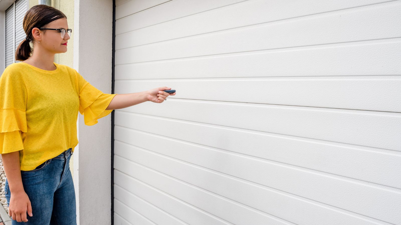 Woman in front of a white garage door. - Garage Door Panel Replacement and Repair